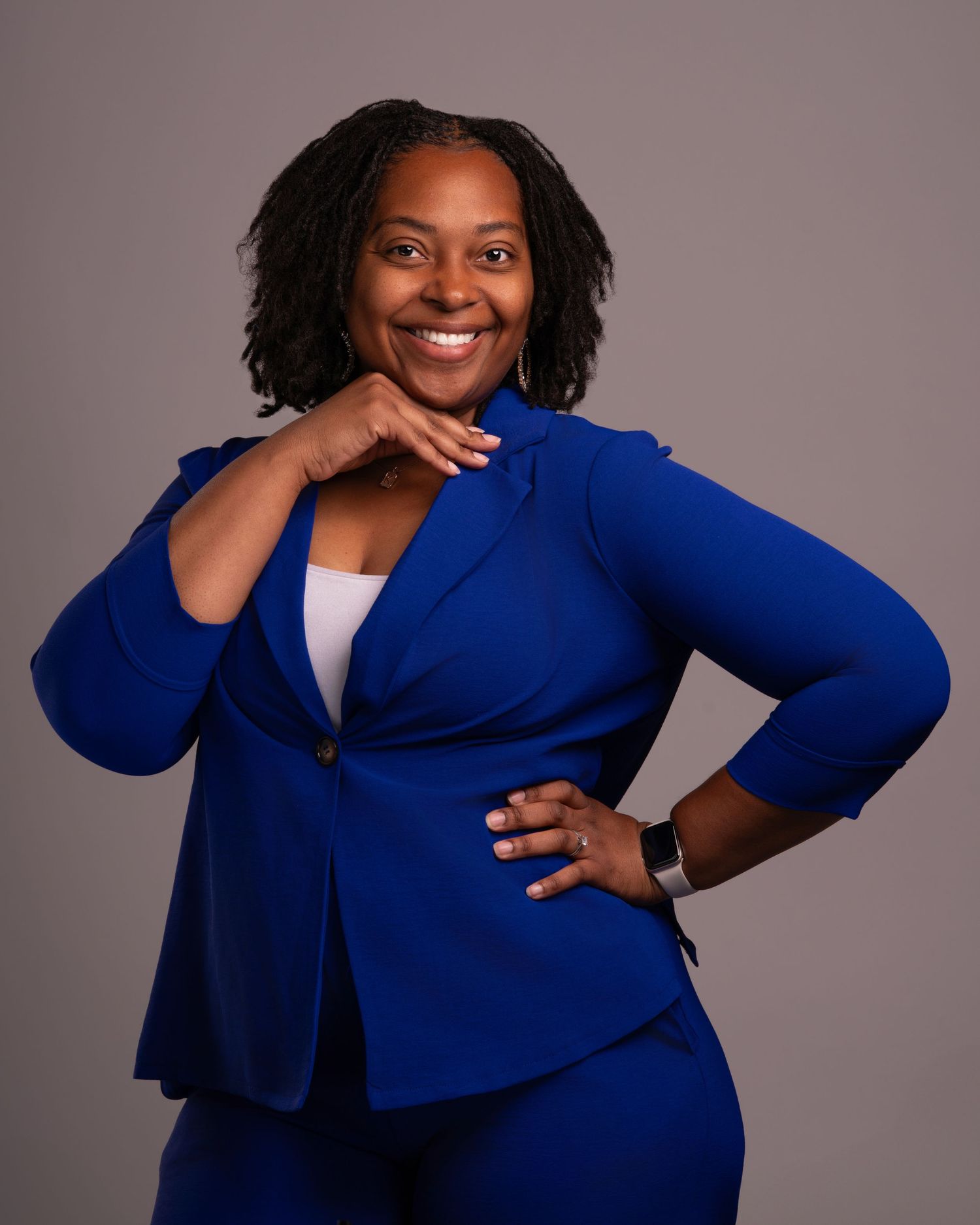 Stylish business portrait in a fitted royal blue suit with confident pose against gray background.