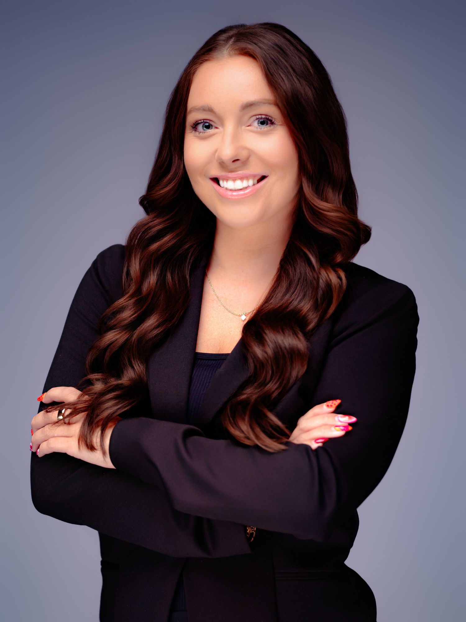 Business portrait featuring crossed arms and professional black attire against studio backdrop.
