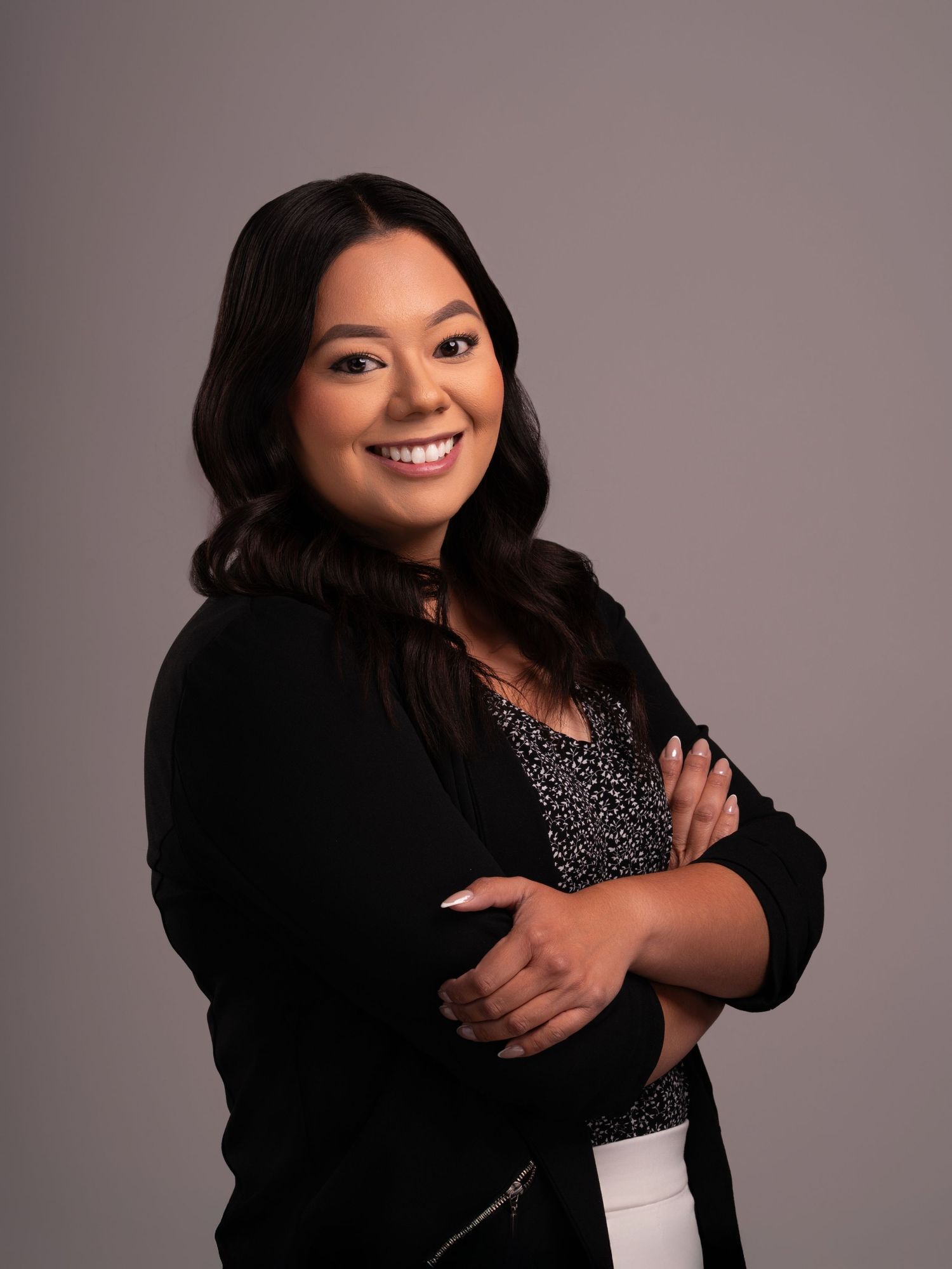 Professional studio portrait in black cardigan and patterned top with styled dark hair.