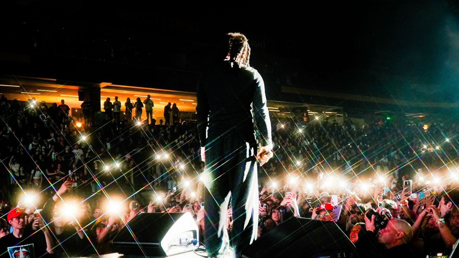 A concert venue at night with colorful stage lights and silhouettes of the crowd.