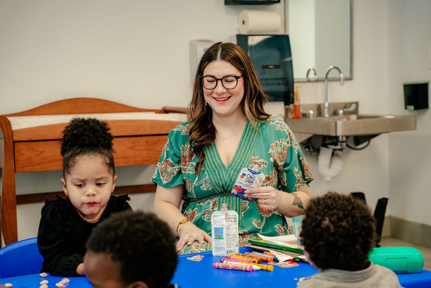 Children and adults gathered around tables during an indoor activity session.