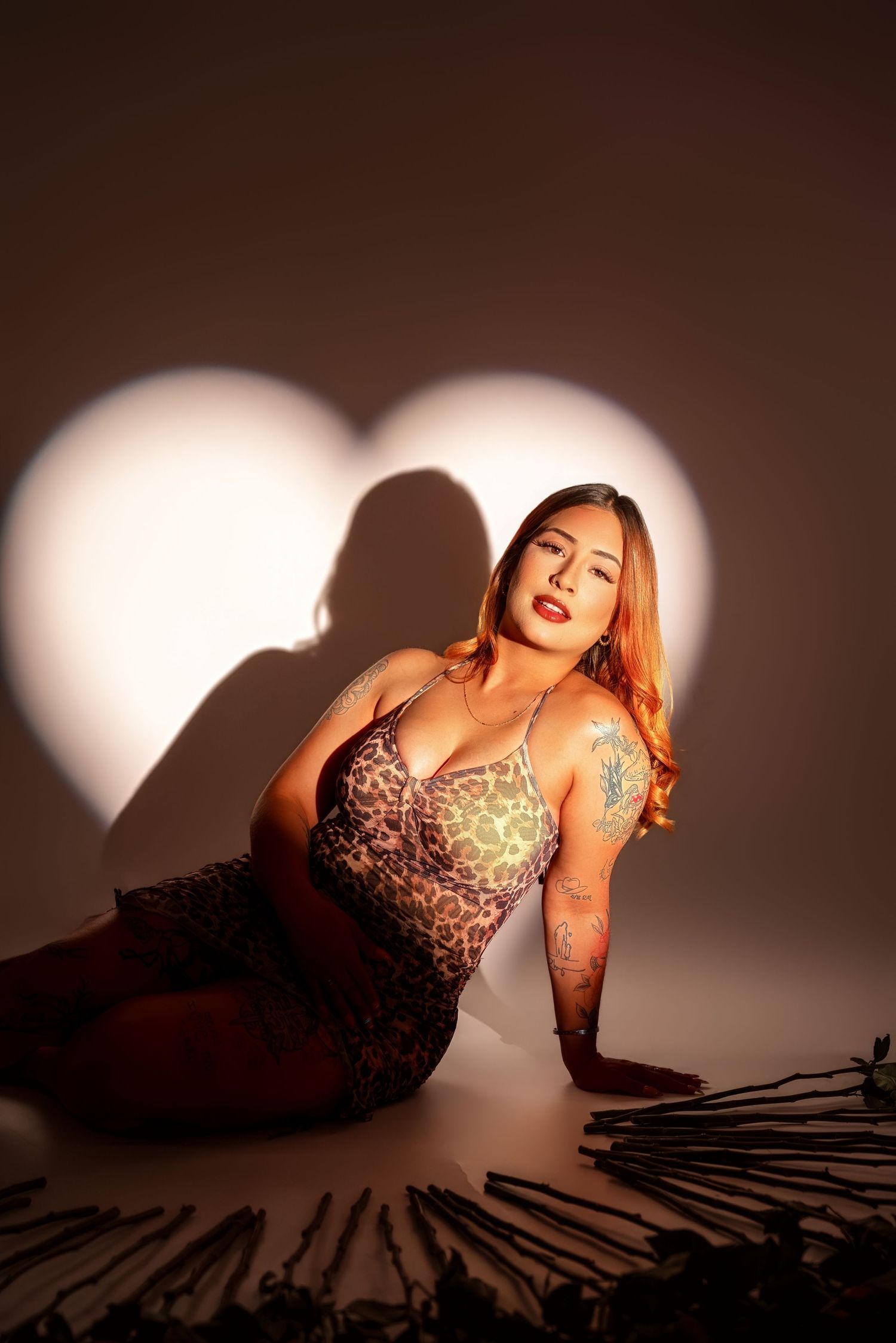 Artistic boudoir photoshoot featuring dramatic lighting and shadows on a dark background.