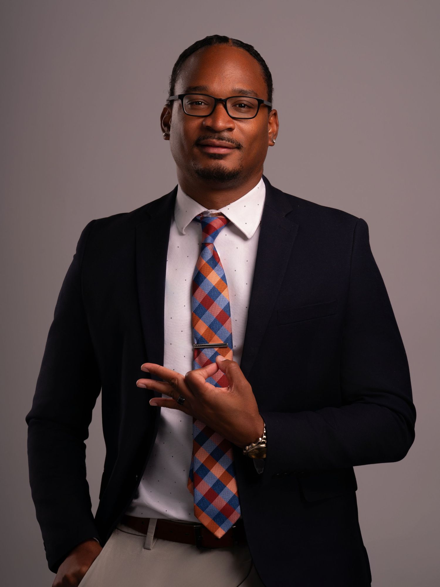 Professional business portrait in dark suit with striped tie and glasses.