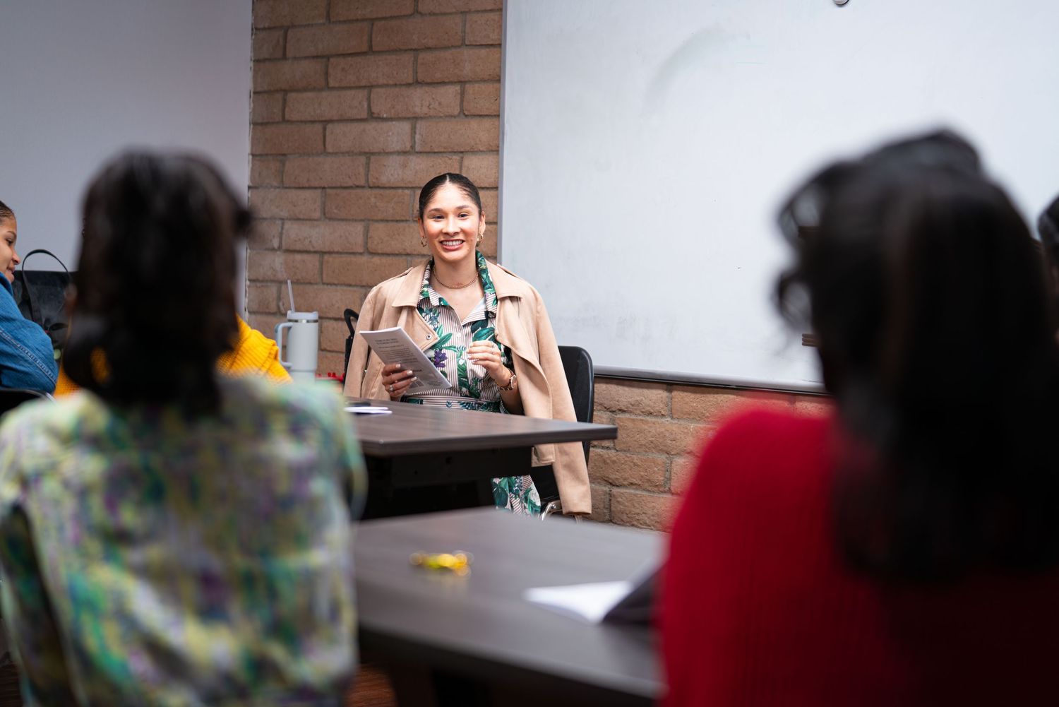Students participate in a classroom discussion with teachers in a brick-walled educational setting.