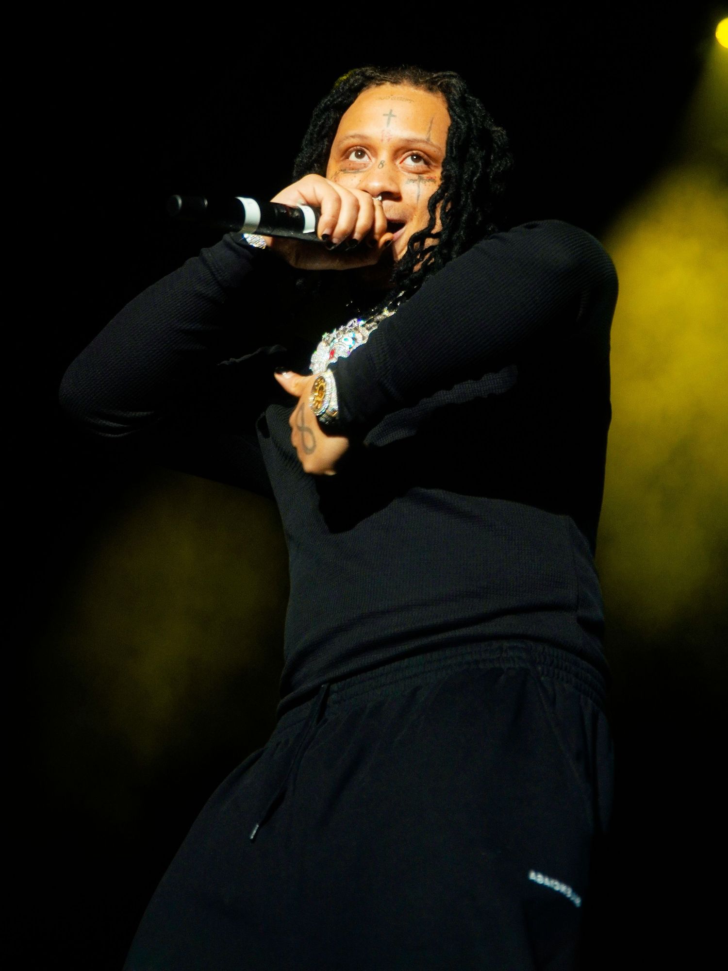 A performer in black clothing on stage during a concert performance.