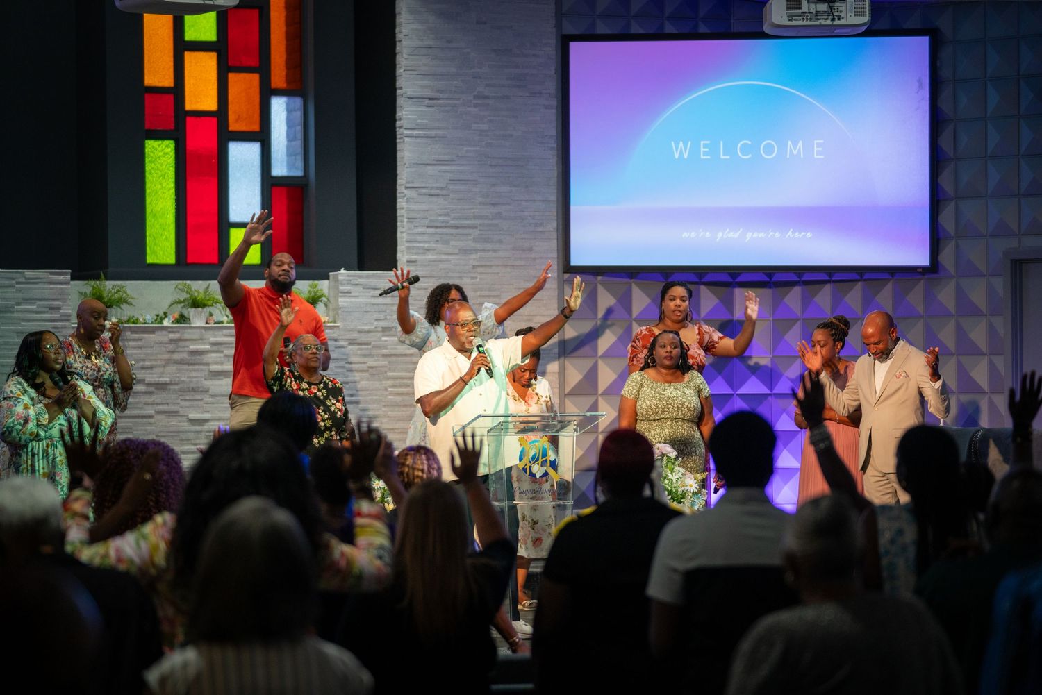 Church or auditorium stage performance with colorful lighting and multiple performers.