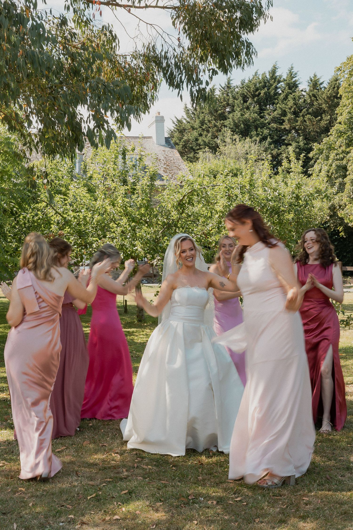 Bridesmaids dancing around bride having fun in the gardens at Anran, South Devon