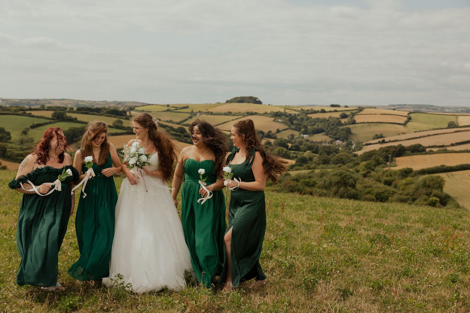 Bride and bridesmaids smiling together in the South Devon countryside on a summer wedding day