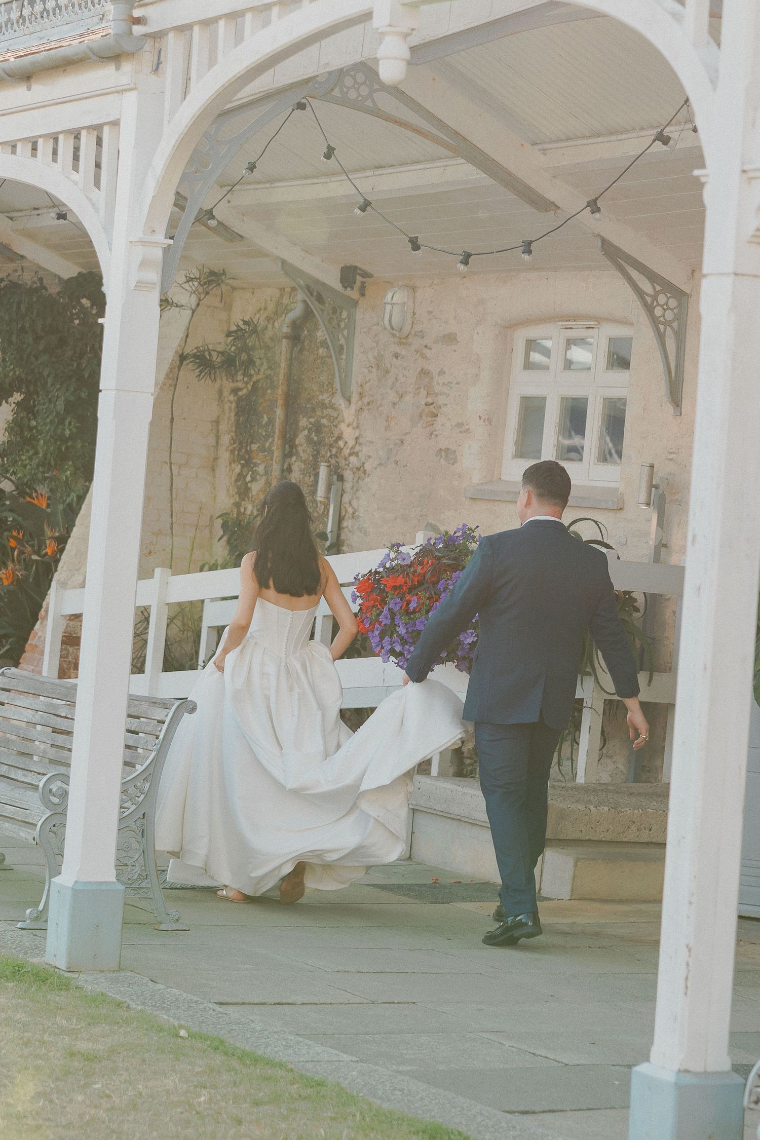 Bride and Groom walking away whilst groom holds dress in Cornwall