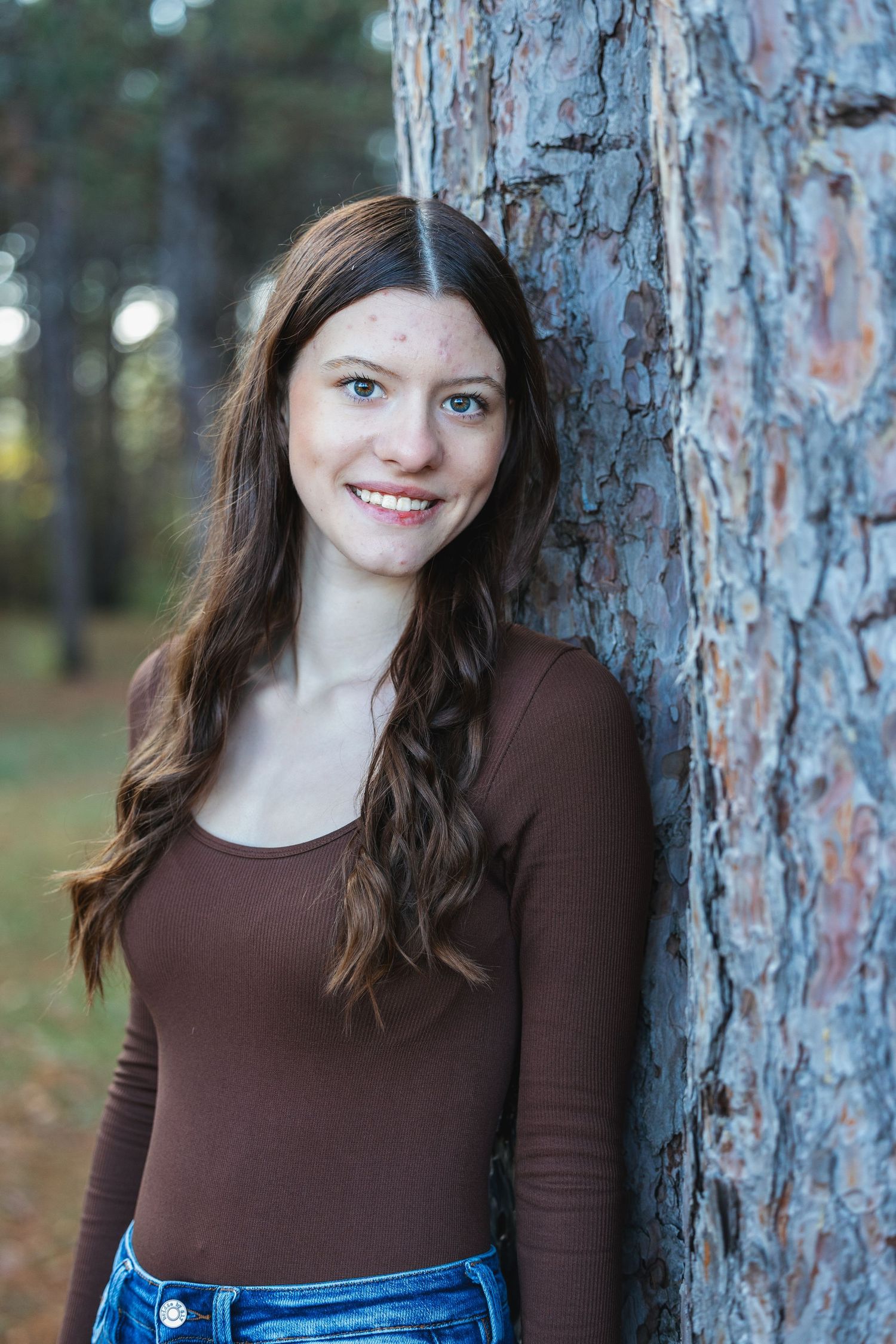 A series of outdoor portrait photos showing someone in a brown long-sleeve top posing against a tree trunk.
