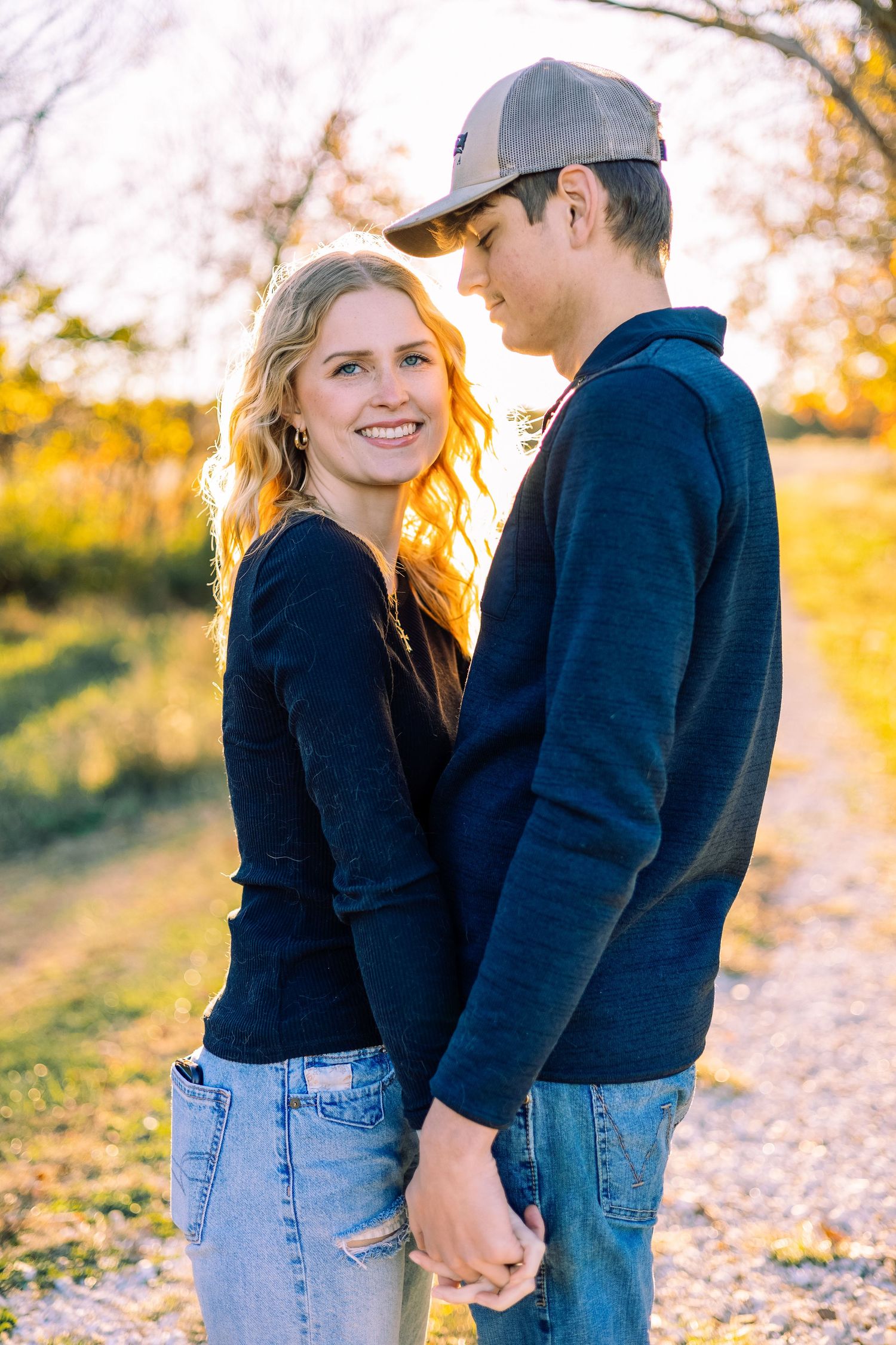 Couple in casual outfits walking hand-in-hand during golden hour sunset.