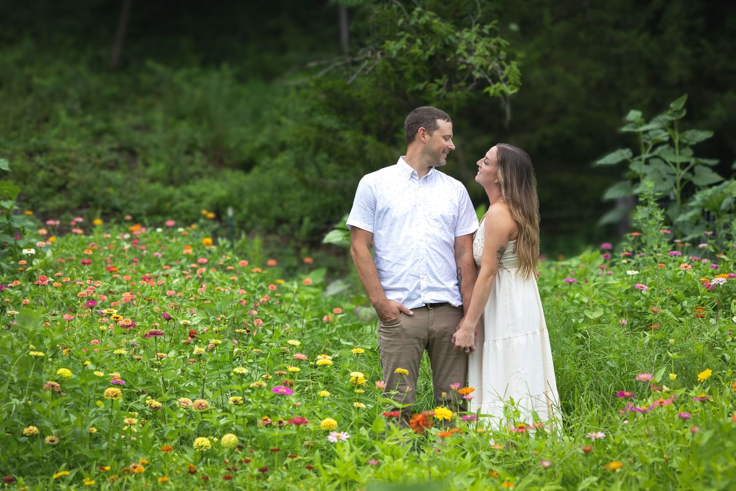 Couple embraces in a scenic wildflower meadow during golden hour photography session.