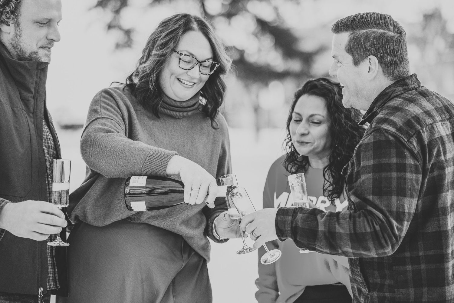 A group of friends enjoying drinks together outdoors in black and white photography.