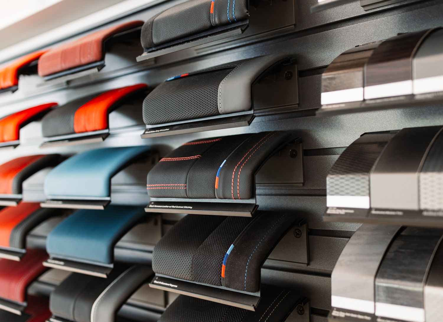 Rows of colorful automotive interior trim samples displayed on shelves in a car customization showroom.
