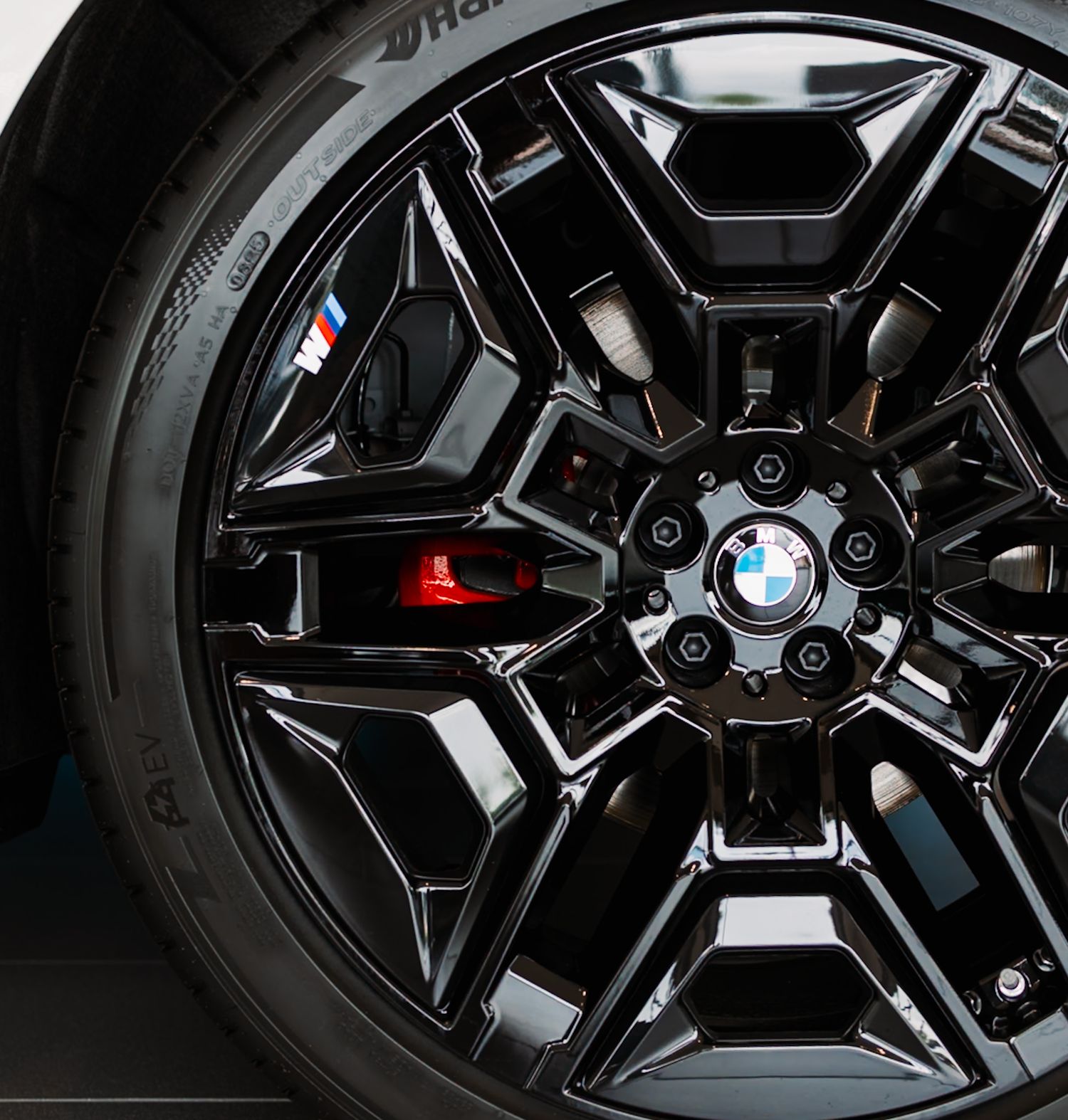 BMW M black alloy wheel with red brake calipers and BMW logo center cap on a high-performance vehicle.