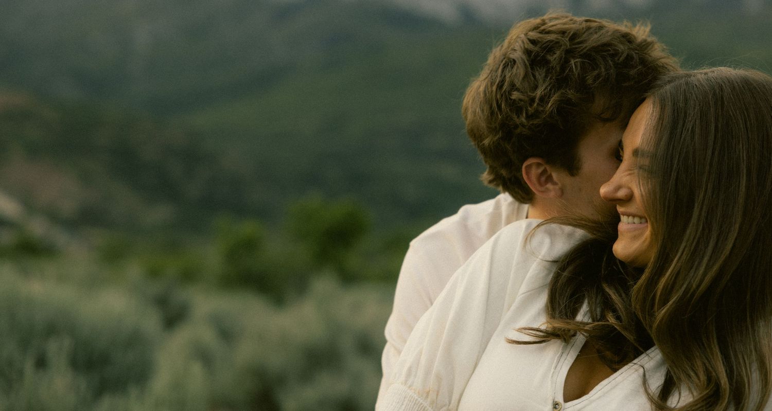 a cinematic filmy photo of two lovers sharing a laugh surrounded by rocky mountains