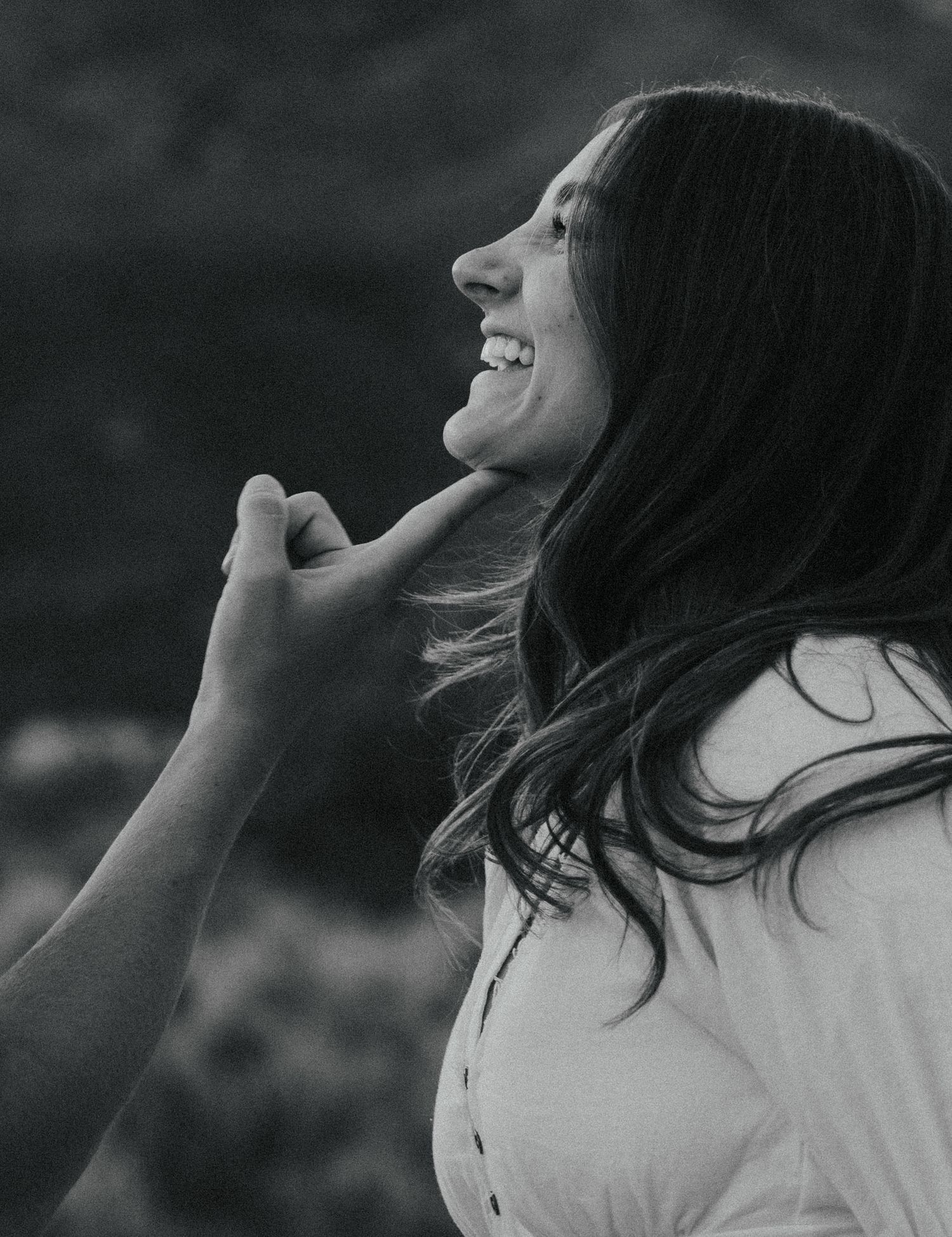 a black and white photo of a man drawing his wife closer in a poppy field in the Utah mountains