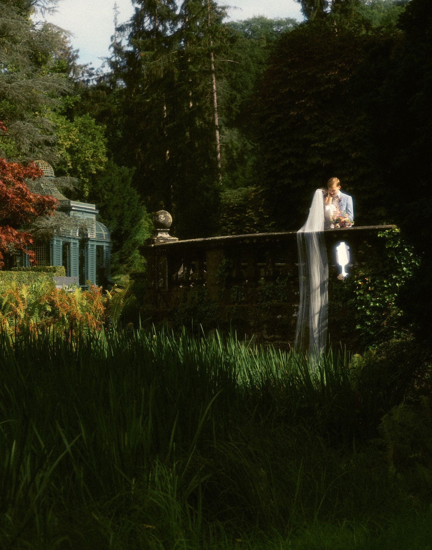 a cinematic dreamy photo of a brides veil cascading down a bridge over a water feature in Switzerland