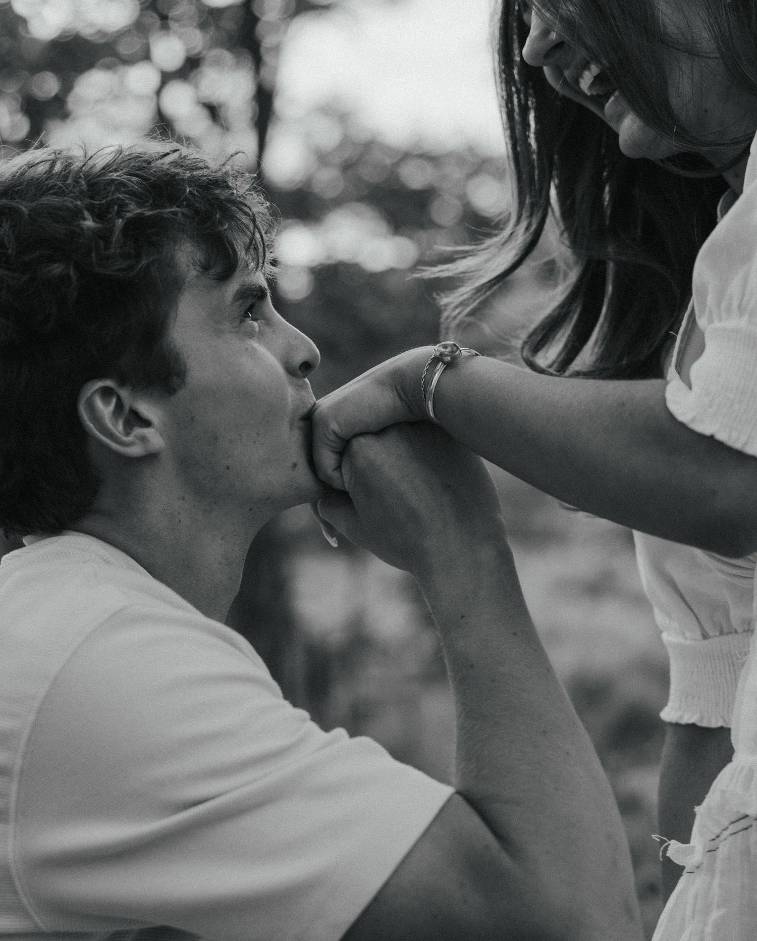 a cinematic black and white photo of a man kissing his wife's hand in a poppy garden