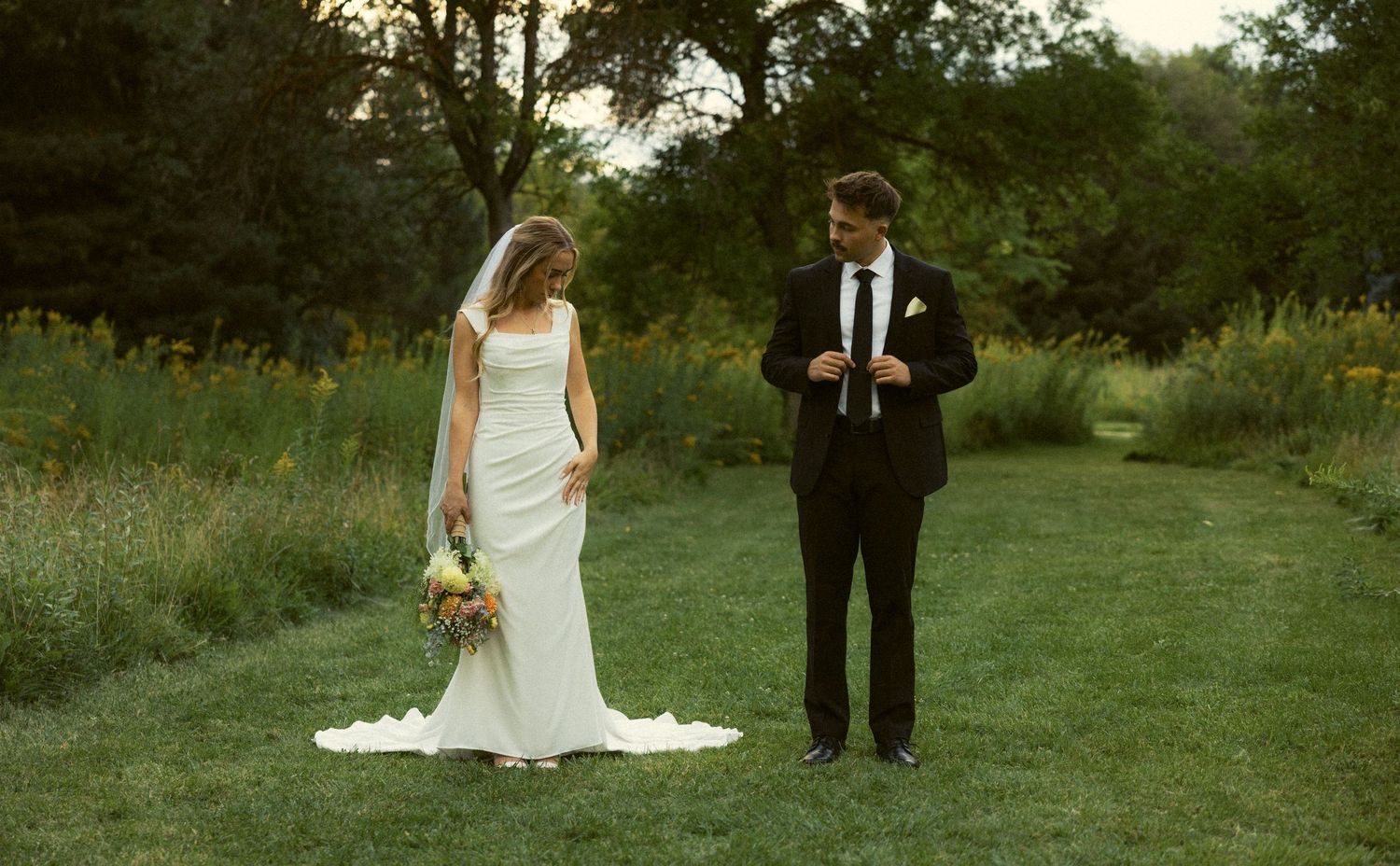 a documentary photo of a groom admiring his bride as they get ready during a bridal session in an Idaho wildflower garden