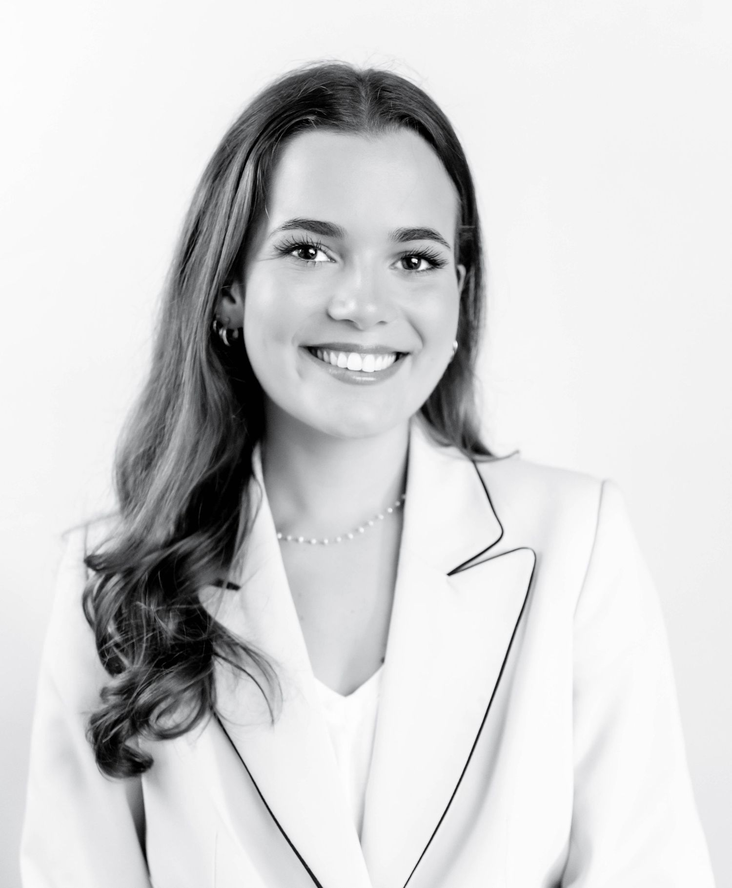 Professional headshot portrait of someone wearing a white blazer against a light background.