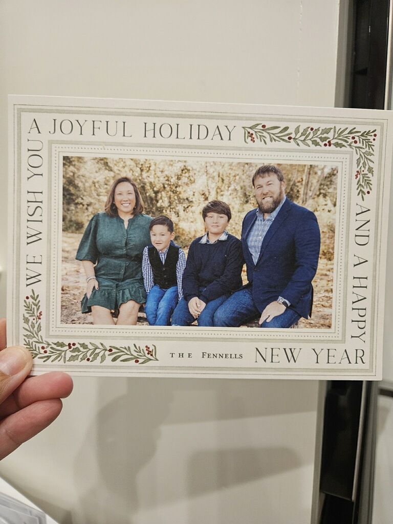 Holiday greeting card design showing a white rectangular banner with decorative foliage elements and text layout.