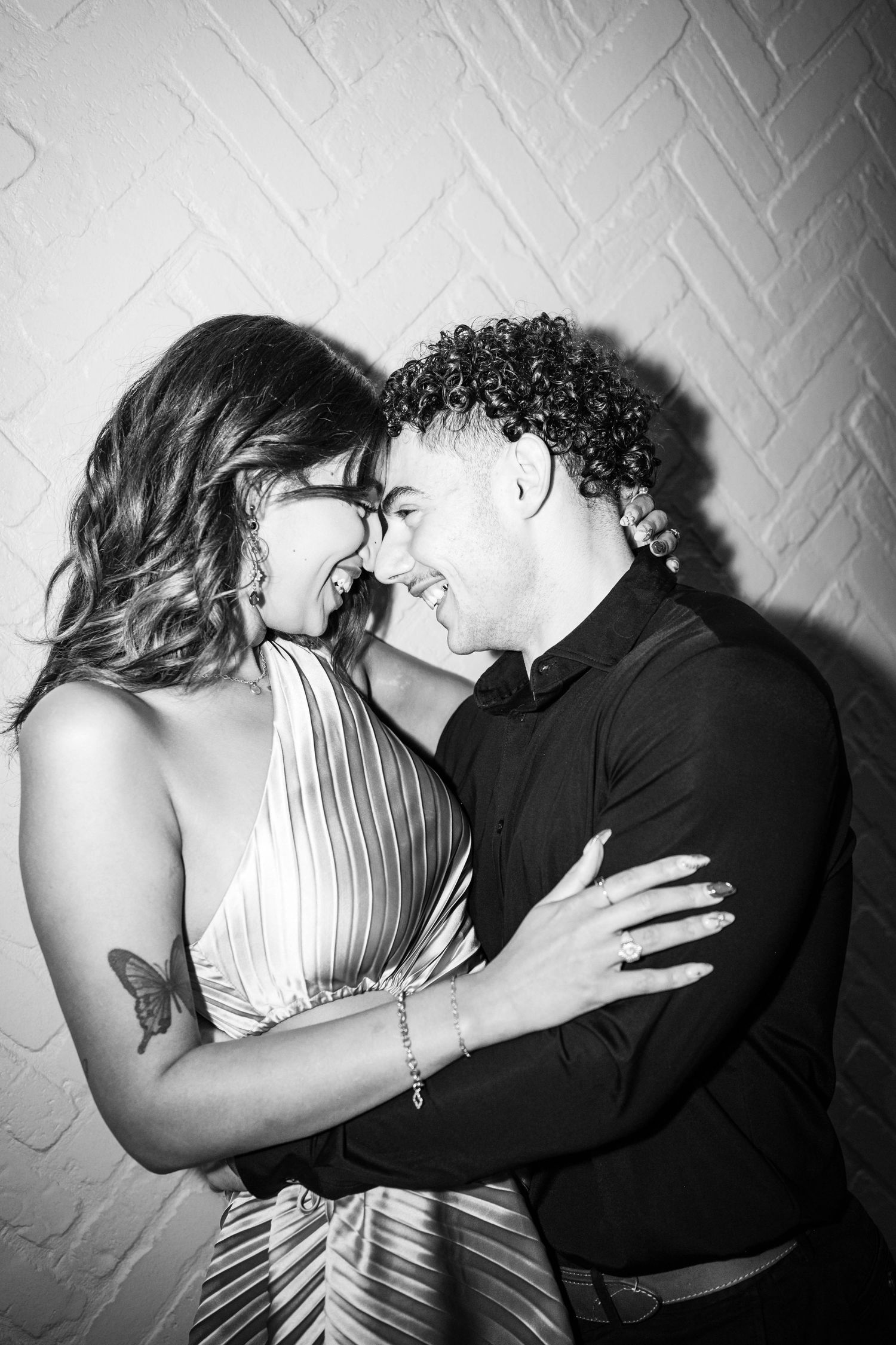 A black and white photo sequence shows a couple in formal attire embracing and kissing against a textured wall.