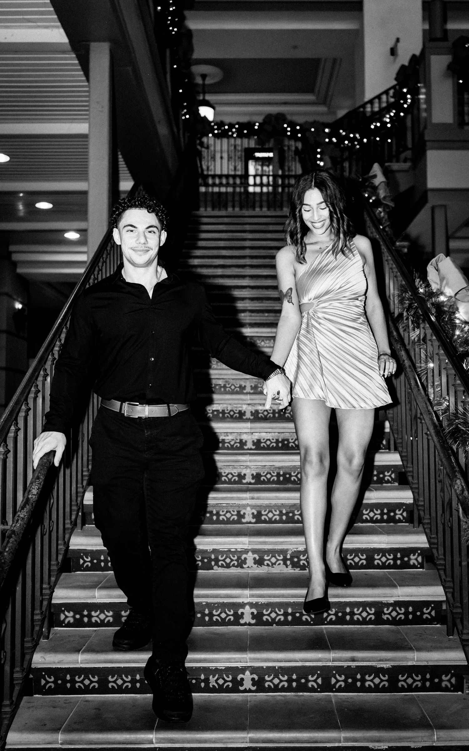 A black and white photo series shows people descending an ornately tiled staircase in formal attire.