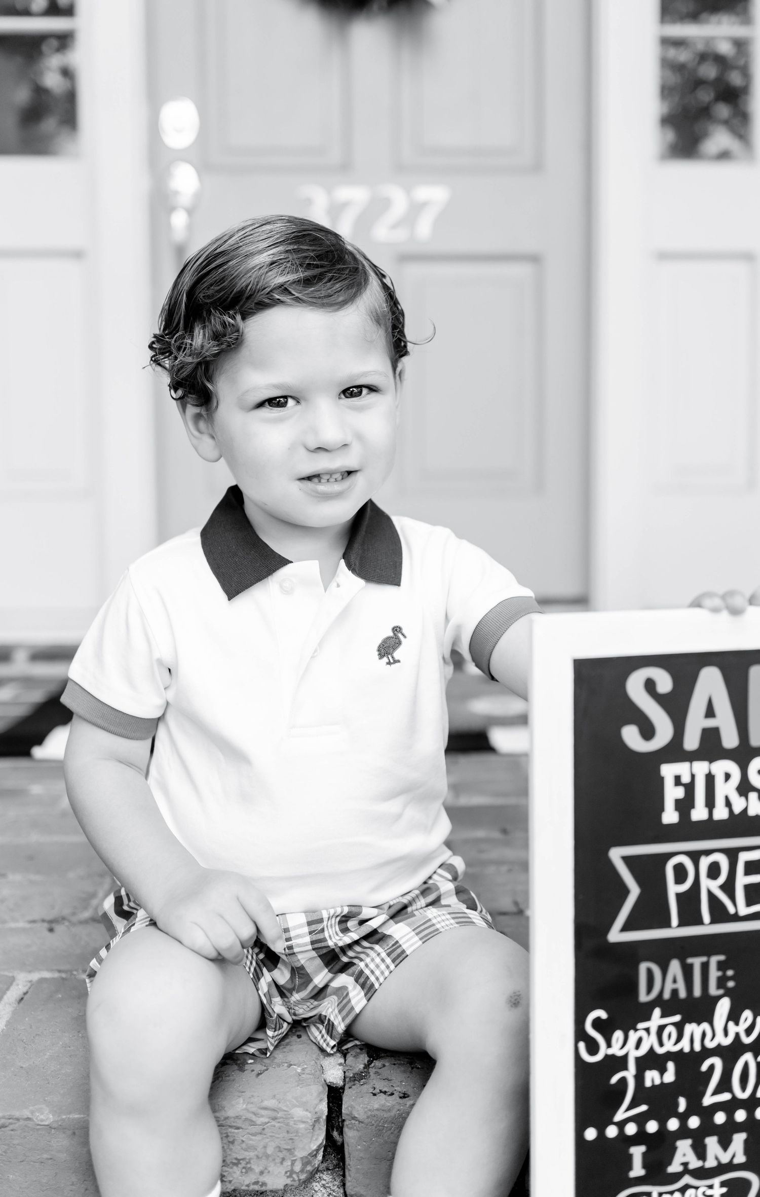 Back-to-school portrait of a young boy in Baton Rouge, sitting on his front porch — natural, timeless photography capturing childhood moment