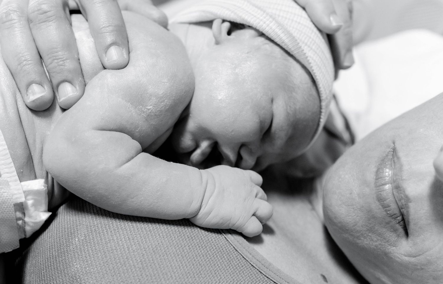Black and white photo of a newborn baby resting on mother's chest during skin-to-skin contact after birth.