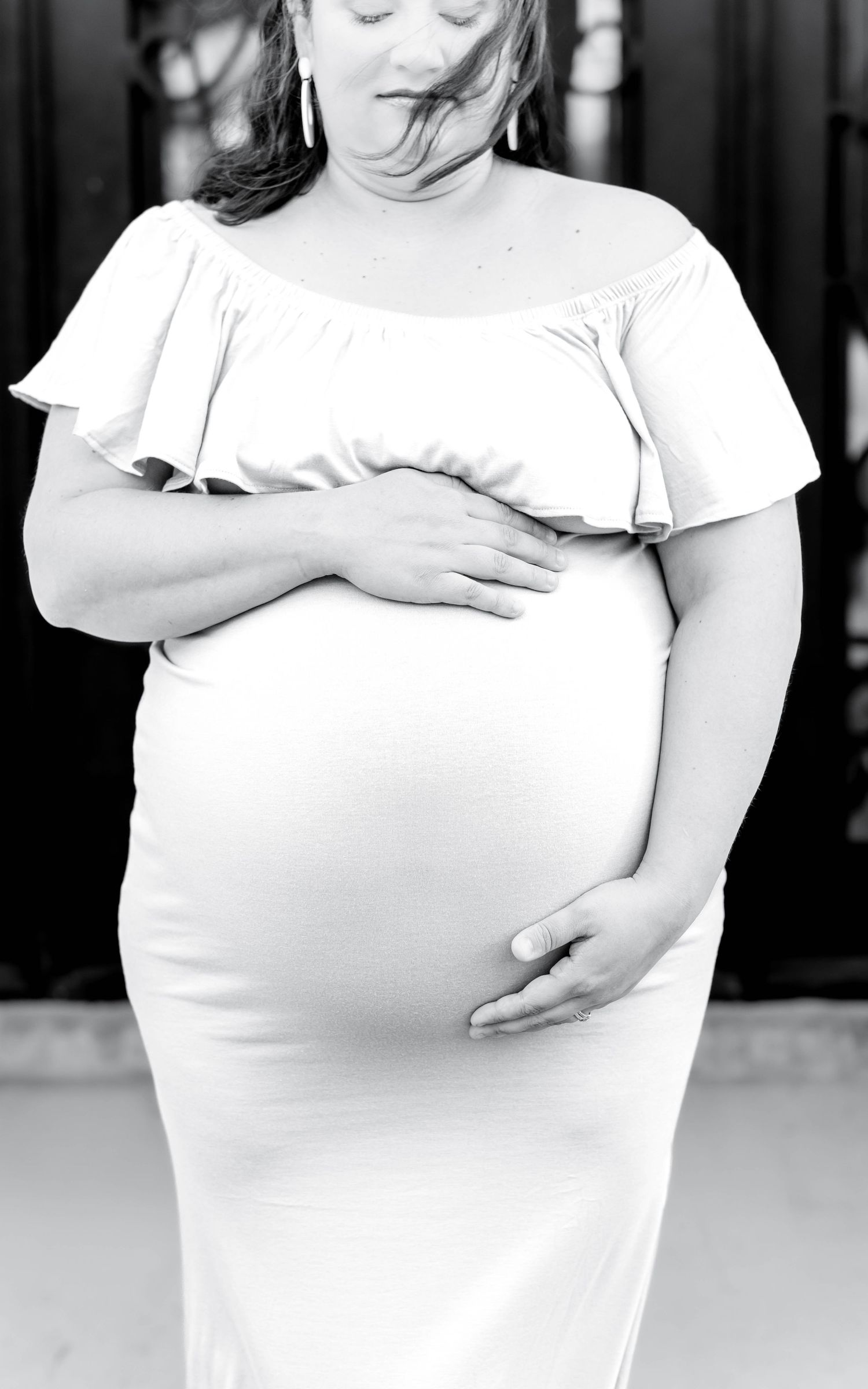 A black and white photo series showing a person in a white top touching their stomach in different poses.