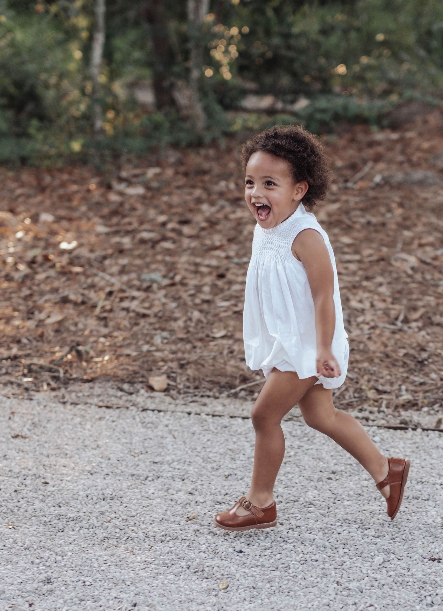 A sequence of photos showing a small child in a white dress skipping and dancing playfully on a gravel path.