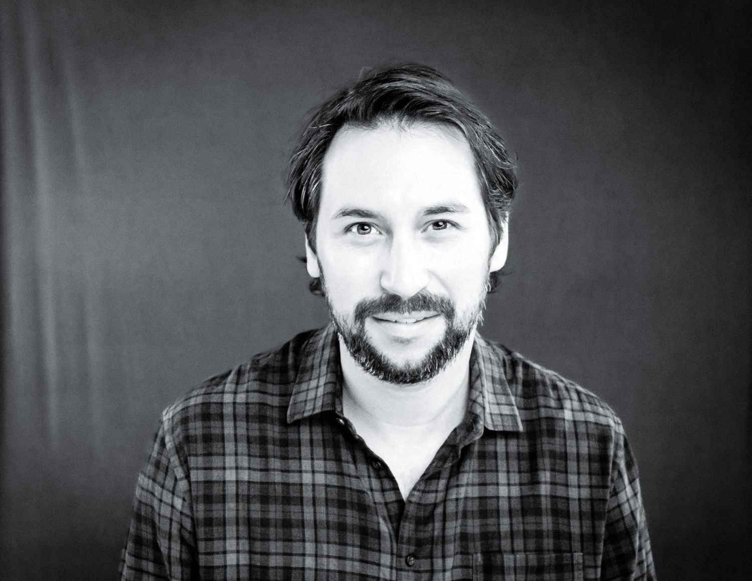 A series of black and white headshot portraits showing different expressions against a dark background.