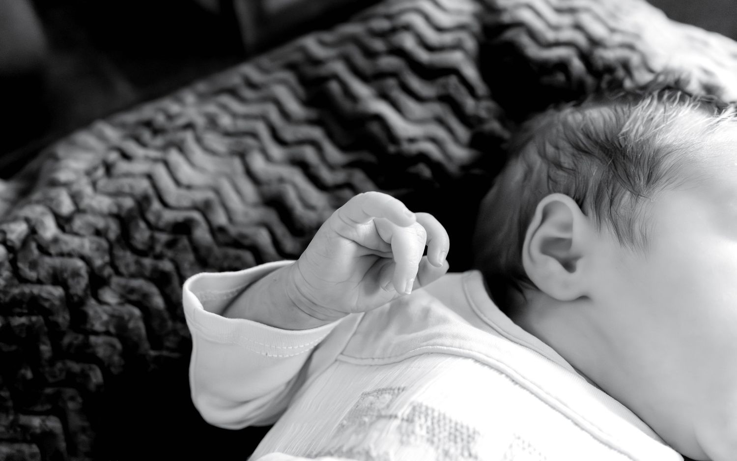 A series of seven black and white close-up photographs showing a sleeping infant in various peaceful poses.