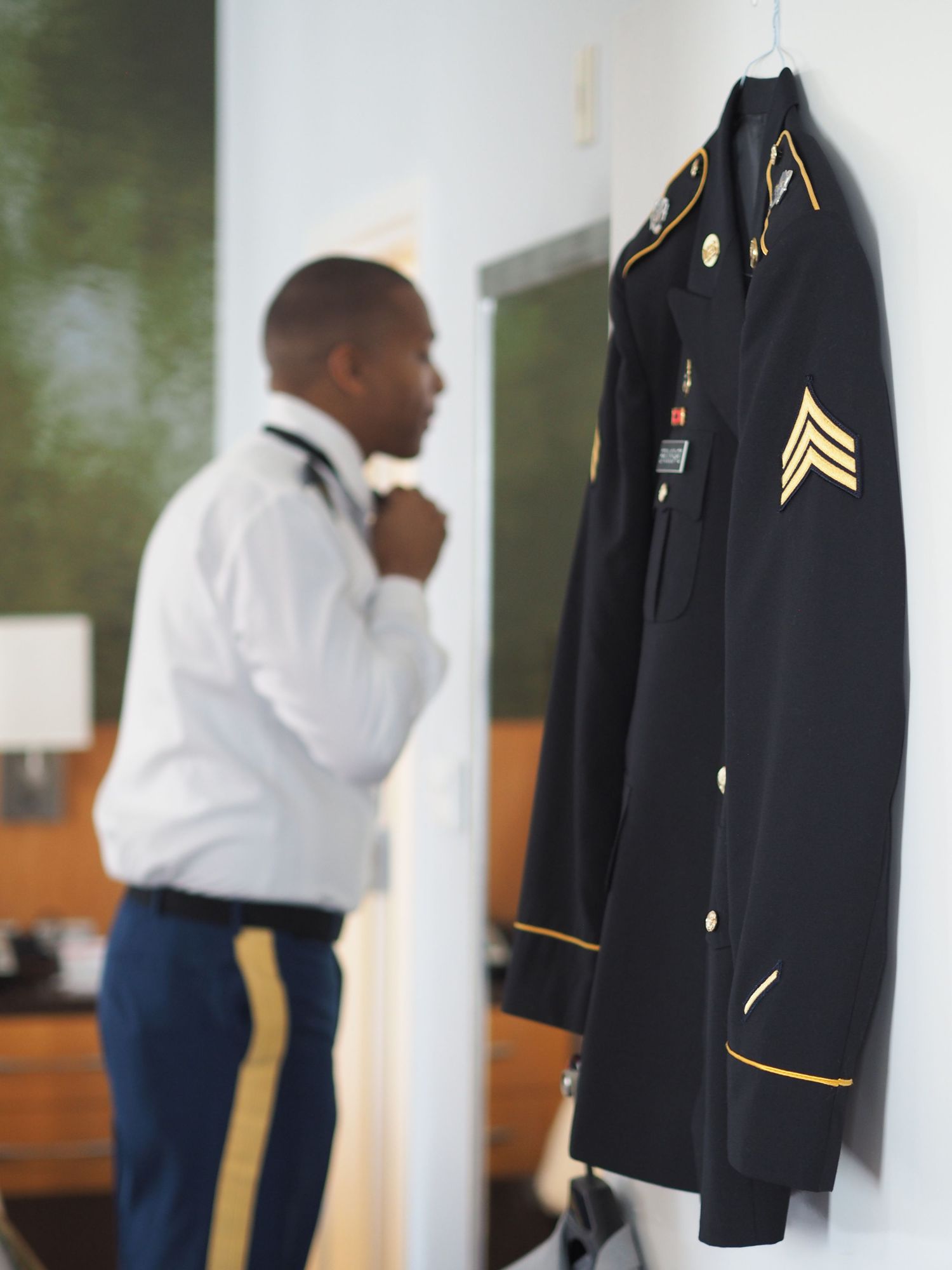 Groom getting dressed before his wedding adjusting his tie at the Baton Rouge Hilton