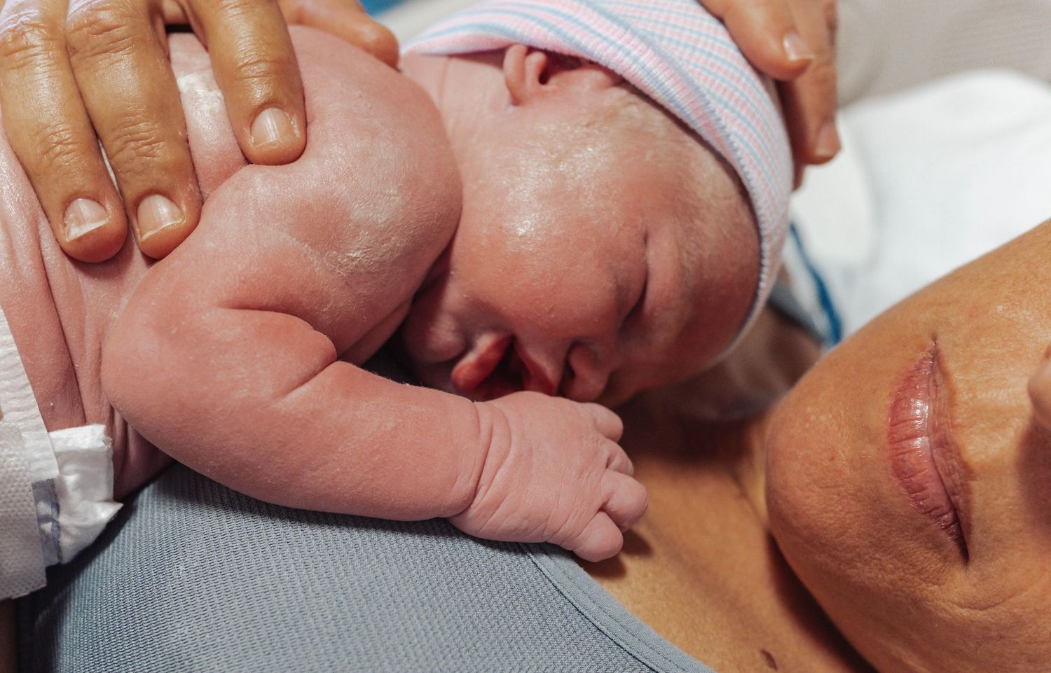 Newborn baby resting on mother's chest during skin-to-skin contact after birth in hospital.