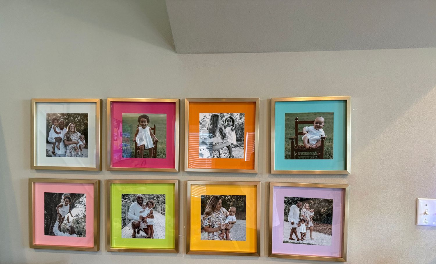 A row of colorful framed photographs hanging on a white wall in a gallery-style display.