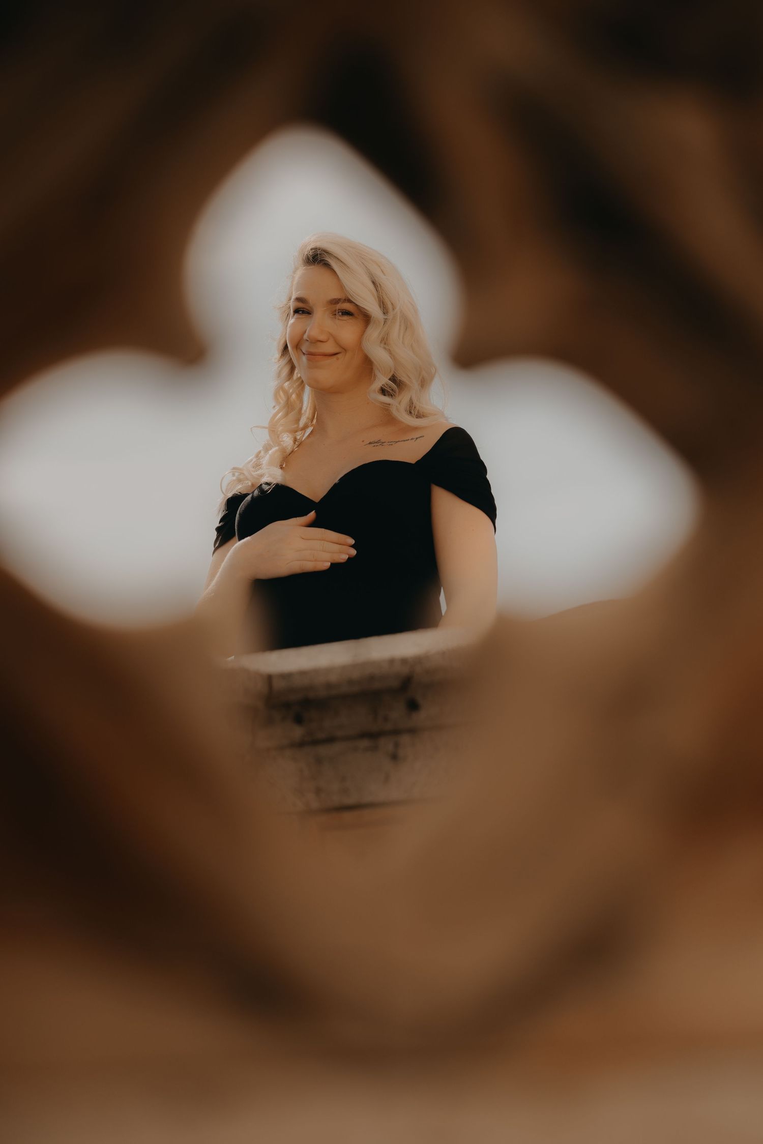 Artistic maternity portrait framed through a decorative stone window opening.