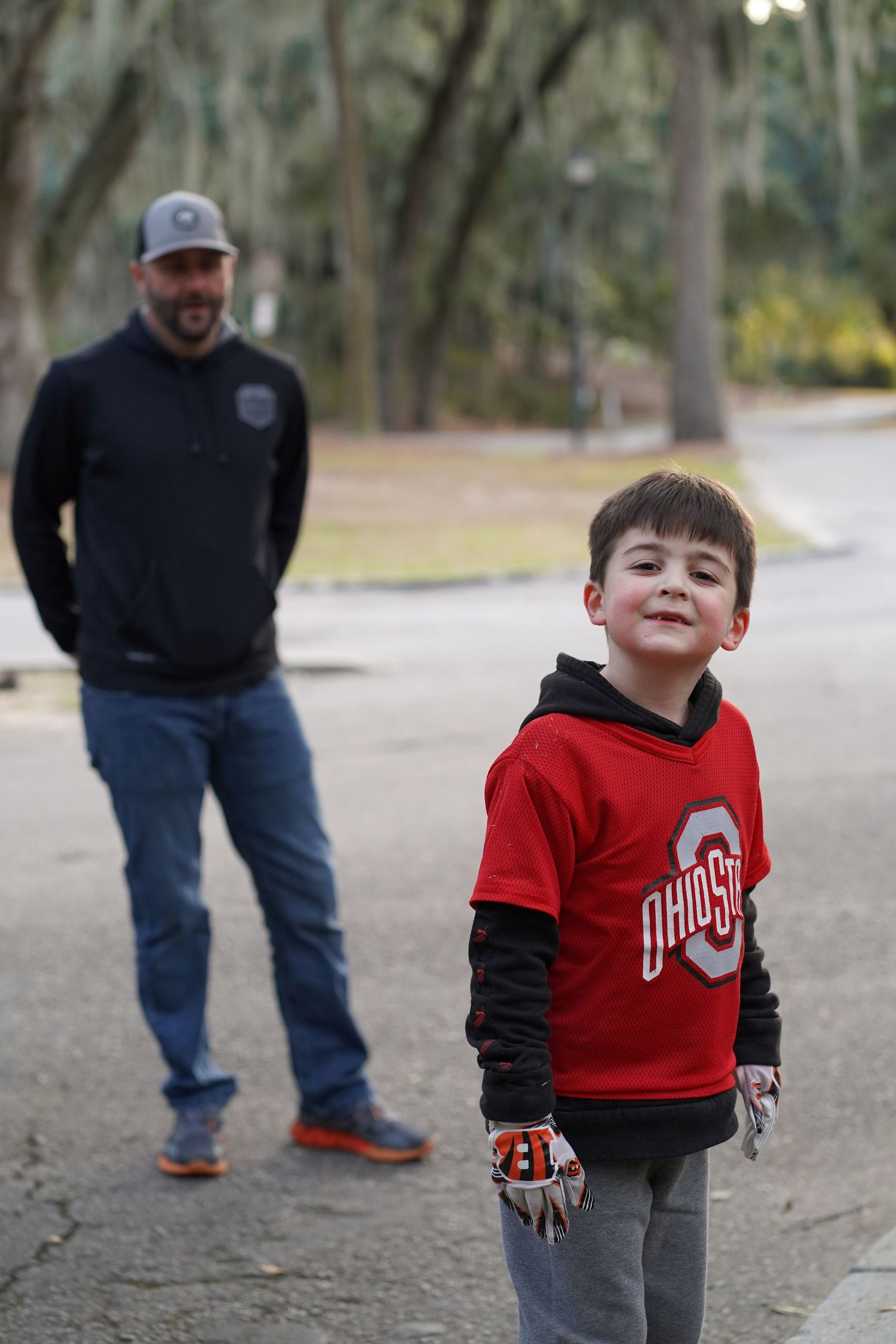 Young child in red and black Ohio State sweatshirt playing outdoors.