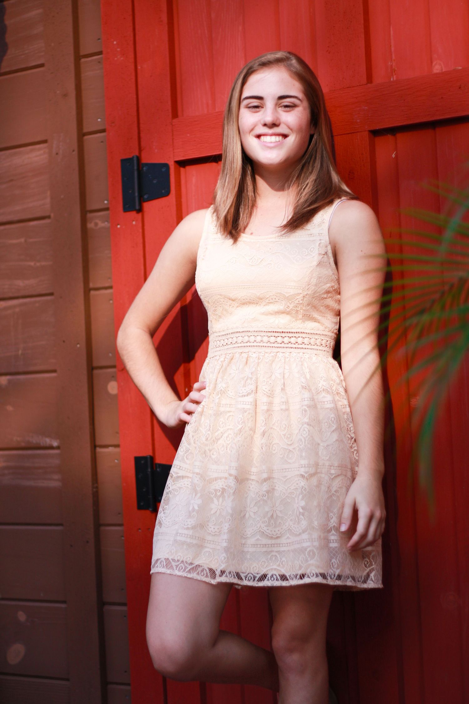 Lace dress photoshoot against a vibrant red wooden wall background.
