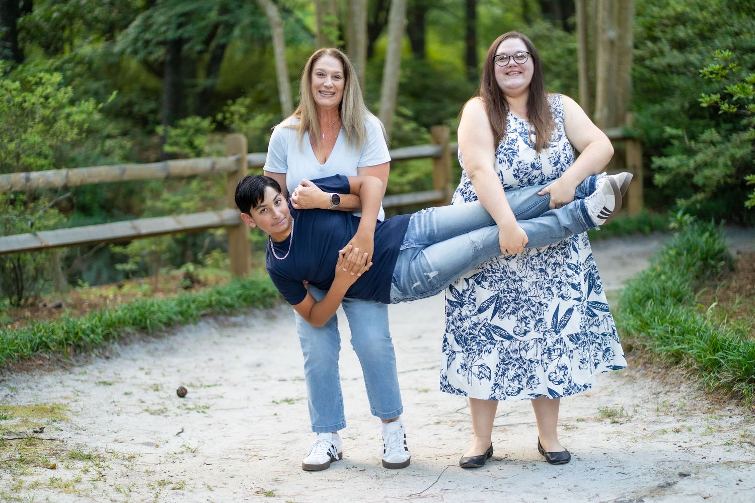 Casual outdoor family photography session on gravel path with wooden fence.