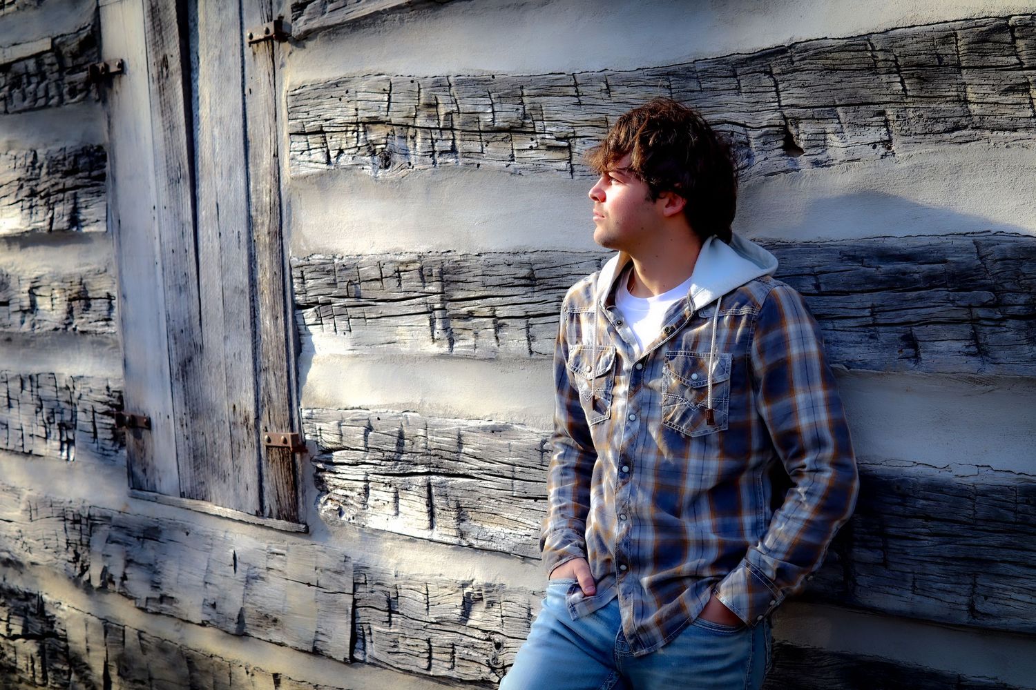 Person in blue plaid shirt sits against stone wall with thoughtful expression in series of repeated images.