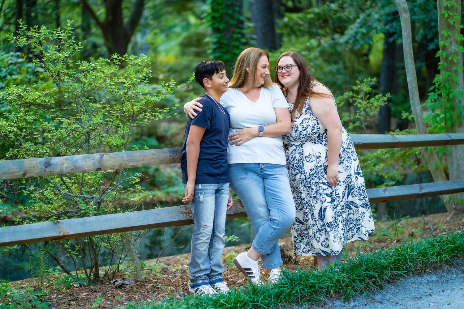 Friends gathering outdoors on wooden fence surrounded by lush green foliage.