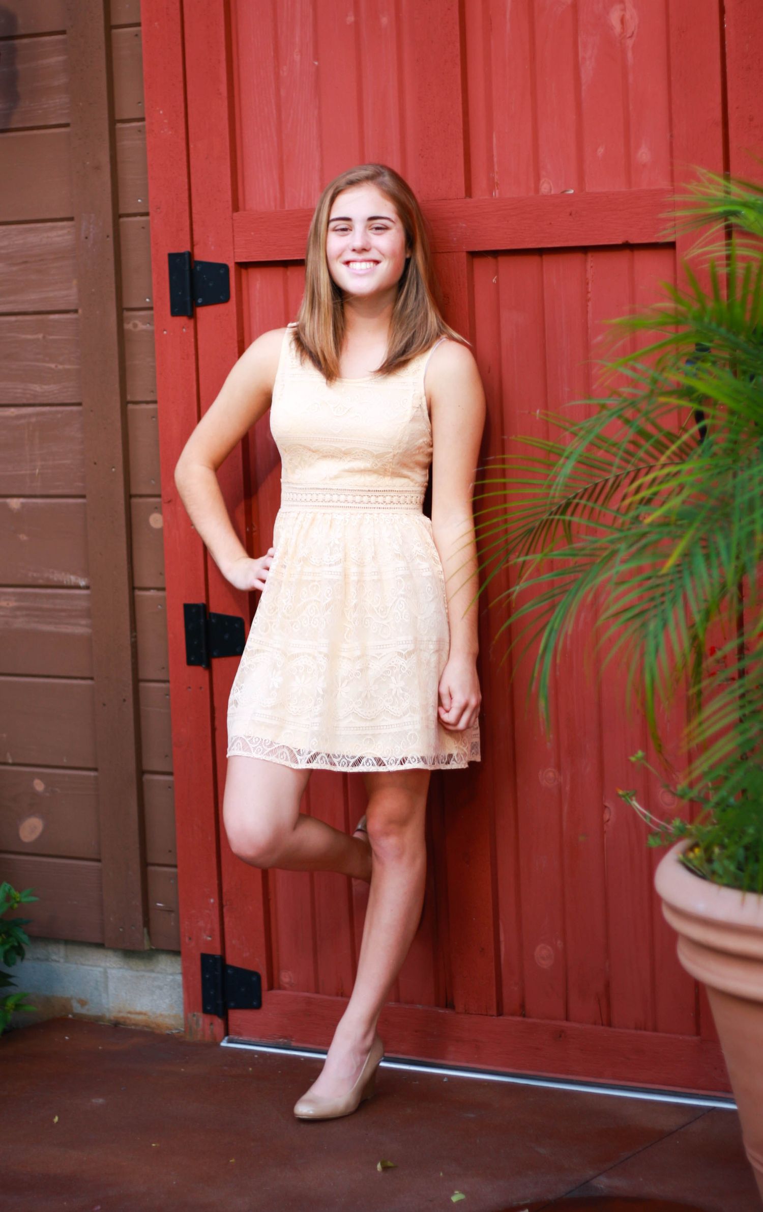 Summer portrait session against a bright red barn with potted plants.