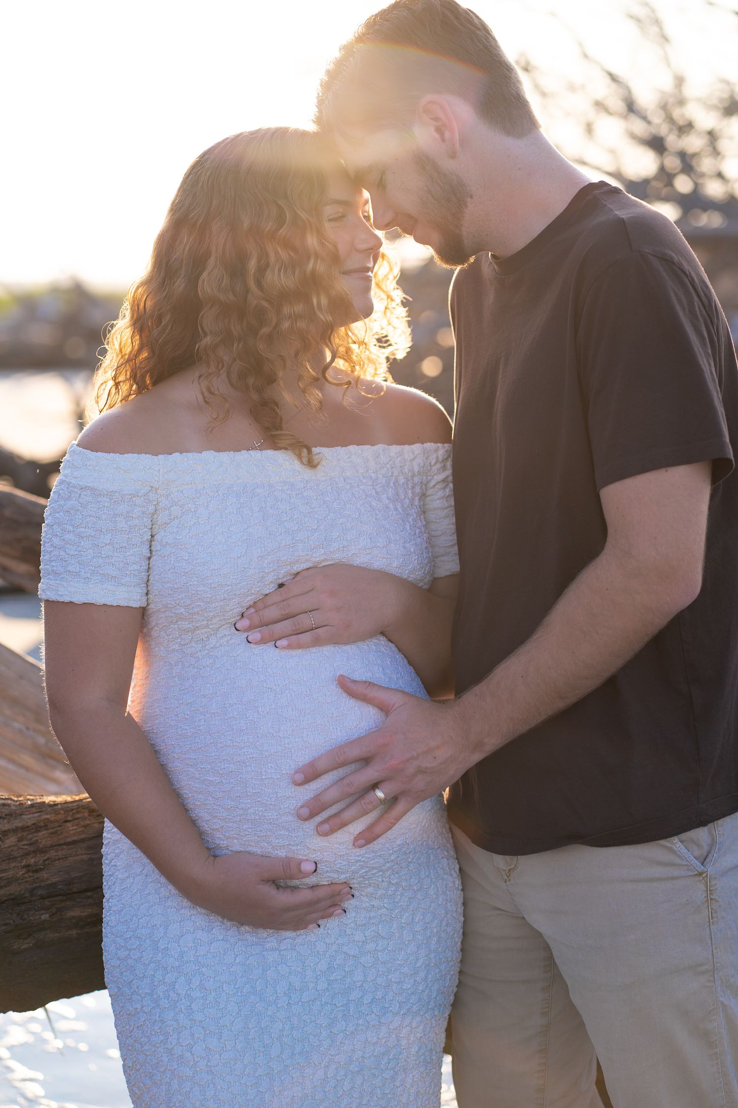A romantic maternity photo session at sunset shows sweet moments of expecting parents in casual attire.