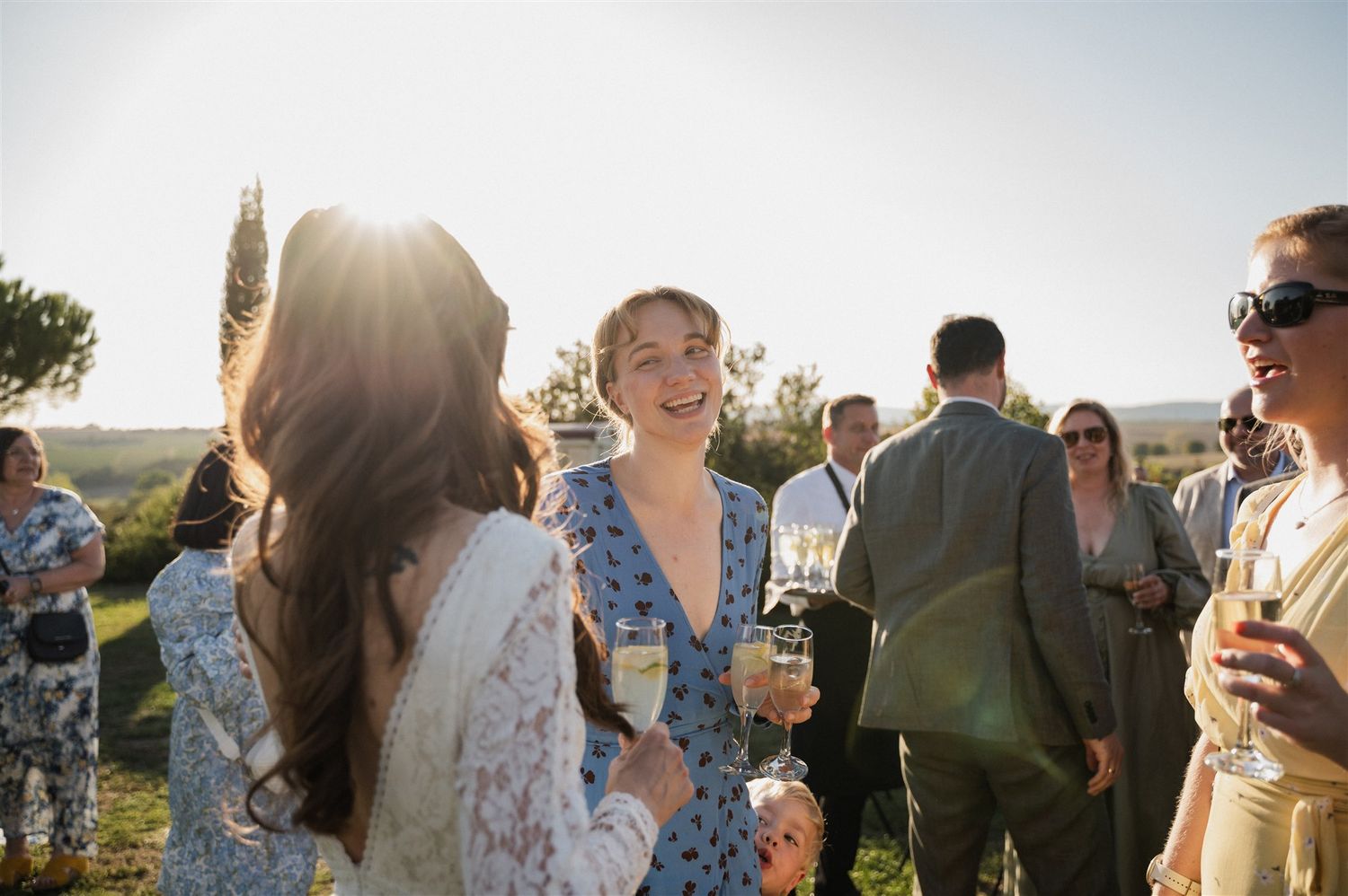 Wedding guests mingling during outdoor cocktail hour at sunset.