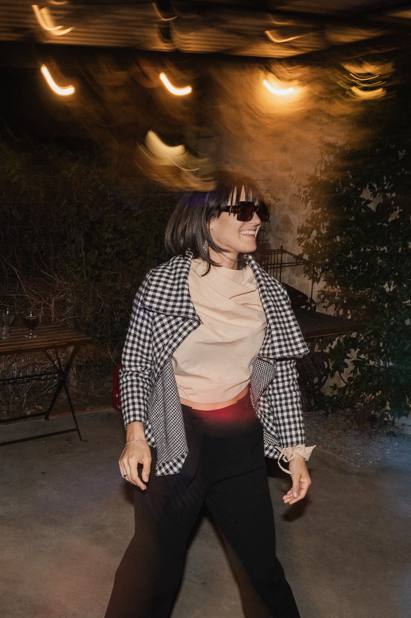 Person in checkered shirt dancing under warm ambient lighting at night.