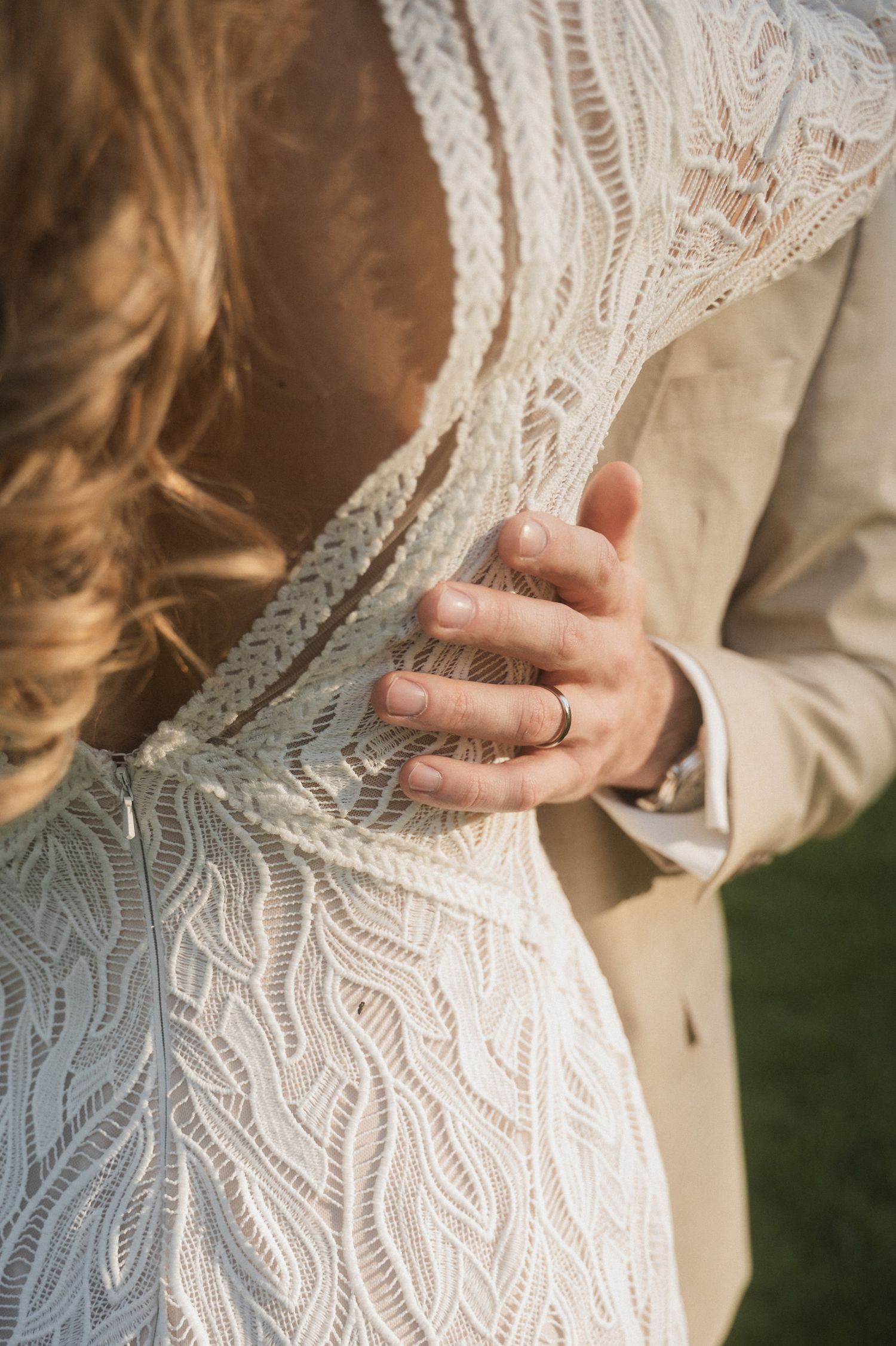 Close-up details of an intricate white lace wedding dress with delicate floral patterns and vintage-inspired design elements.