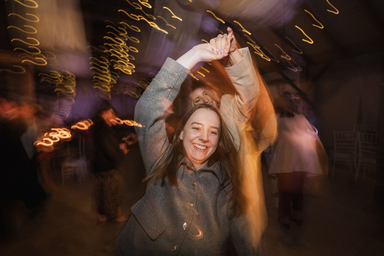 Motion blur captures dancers moving energetically on a dark dance floor with warm lighting and streaks of movement.
