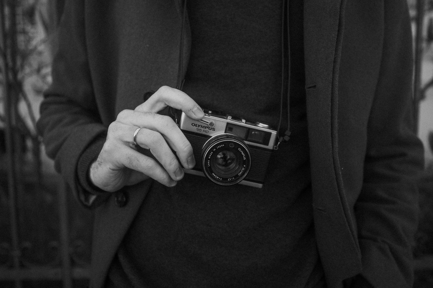 A black and white series of close-up shots showing hands holding vintage cameras against a dark background.